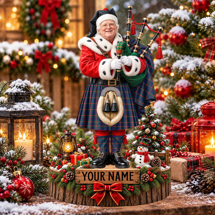 Personalized Christmas piper plaque in the Agnew Modern tartan, standing on a snowy log base with a name plaque