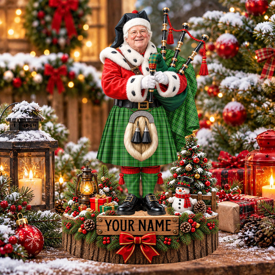Personalized Christmas piper plaque in the Blane 1 tartan, standing on a snowy log base with a name plaque