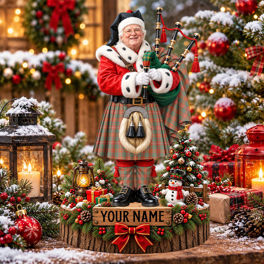 Personalized Christmas piper plaque in the Bruce Ancient tartan, standing on a snowy log base with a name plaque