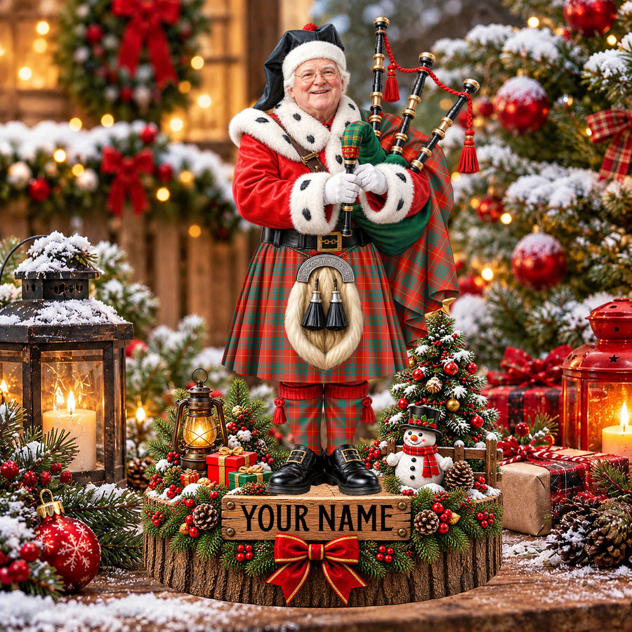 Personalized Christmas piper plaque in the Cameron Ancient tartan, standing on a snowy log base with a name plaque