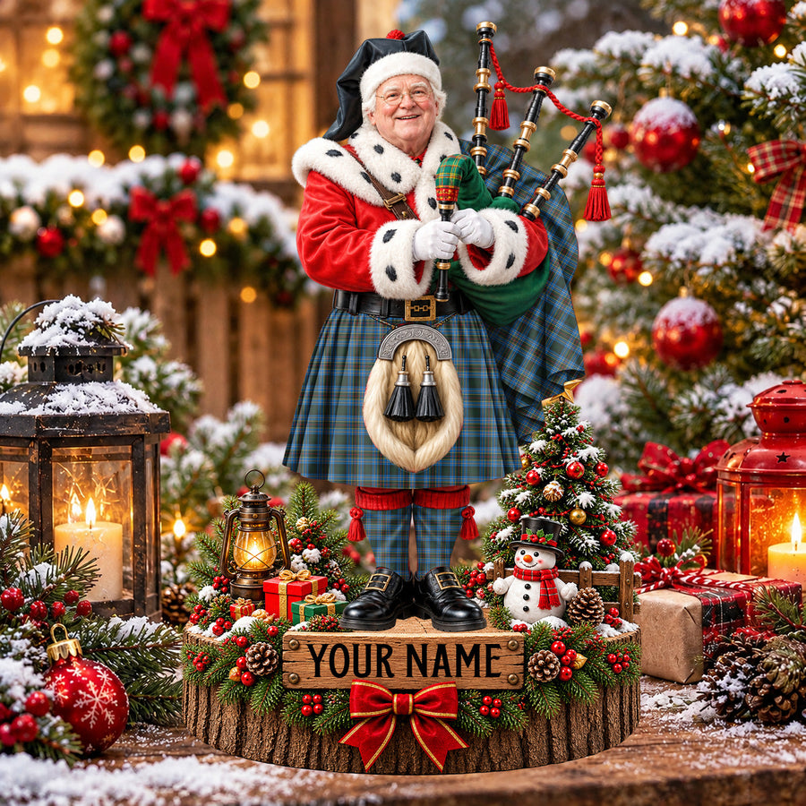 Personalized Christmas piper plaque in the Cockburn Modern tartan, standing on a snowy log base with a name plaque