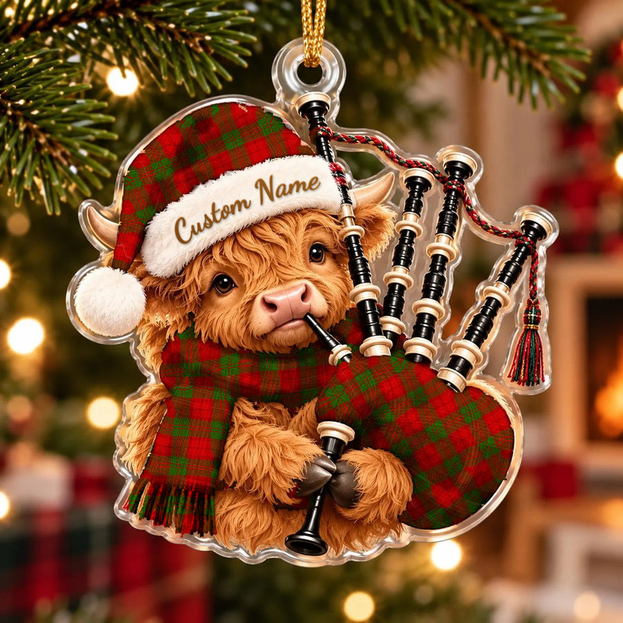Acrylic Highland cow calf ornament playing the bagpipes, in a Dewar tartan Santa hat, scarf and pipe bag, with a custom name on the hat