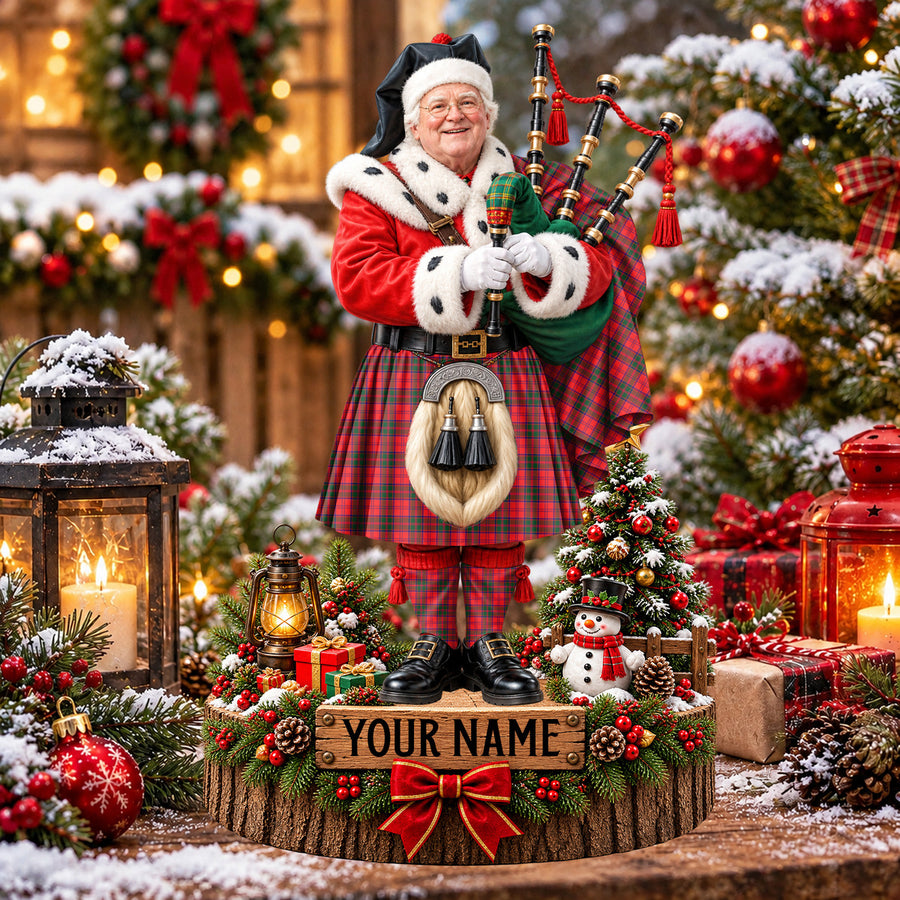 Personalized Christmas piper plaque in the Drummond Modern tartan, standing on a snowy log base with a name plaque