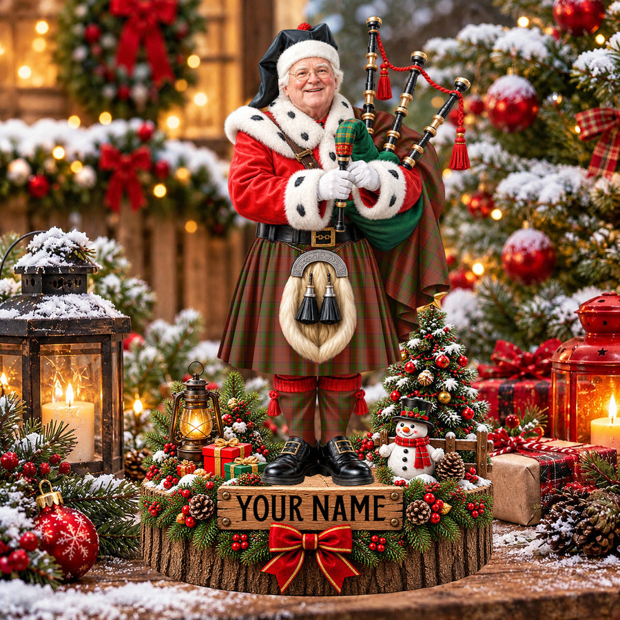 Personalized Christmas piper plaque in the Drummond tartan, standing on a snowy log base with a name plaque