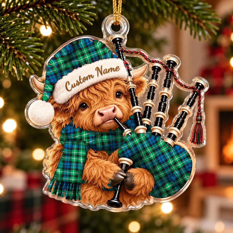 Acrylic Highland cow calf ornament playing the bagpipes, in a Graham of Montrose Ancient tartan Santa hat, scarf and pipe bag, with a custom name on the hat
