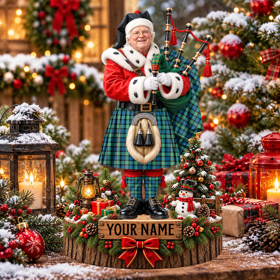 Personalized Christmas piper plaque in the Gunn Ancient tartan, standing on a snowy log base with a name plaque