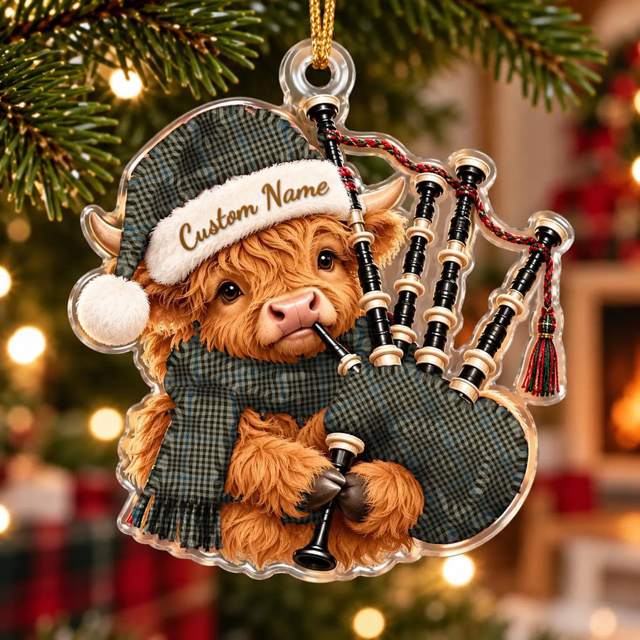 Acrylic Highland cow calf ornament playing the bagpipes, in a Haig Check tartan Santa hat, scarf and pipe bag, with a custom name on the hat