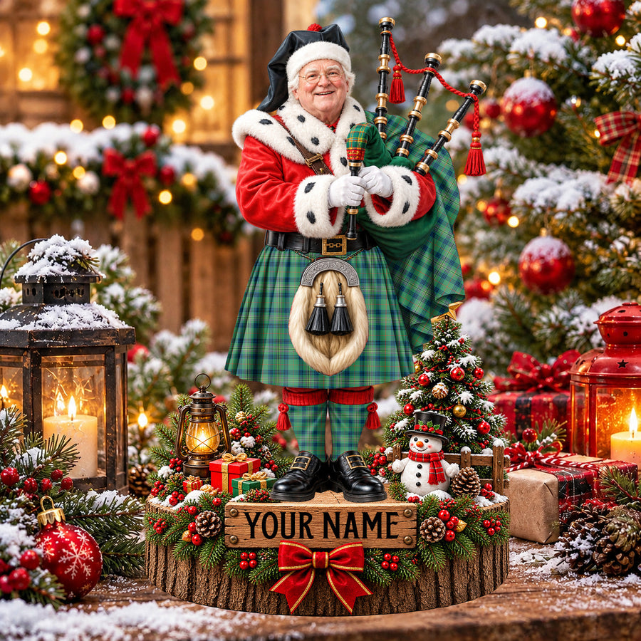 Personalized Christmas piper plaque in the Kennedy Ancient tartan, standing on a snowy log base with a name plaque