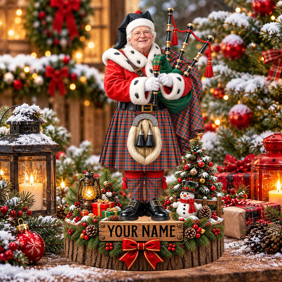 Personalized Christmas piper plaque in the MacDuff Ancient tartan, standing on a snowy log base with a name plaque