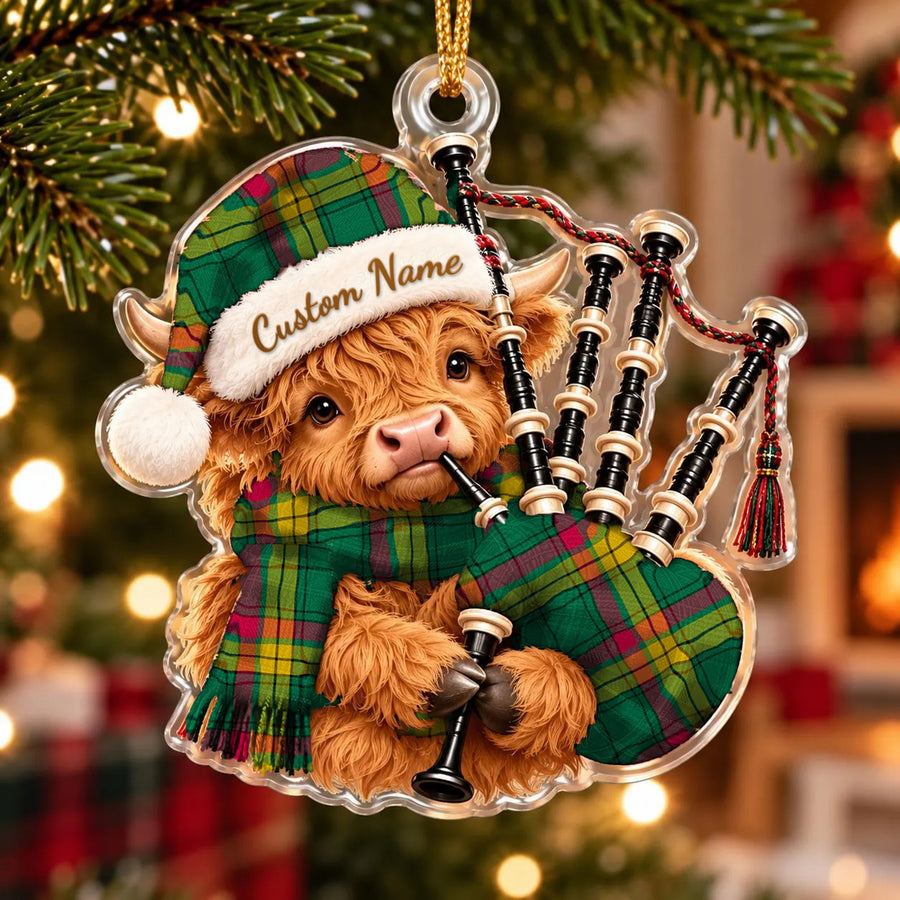 Acrylic Highland cow calf ornament playing the bagpipes, in a MacMillan Old Ancient tartan Santa hat, scarf and pipe bag, with a custom name on the hat