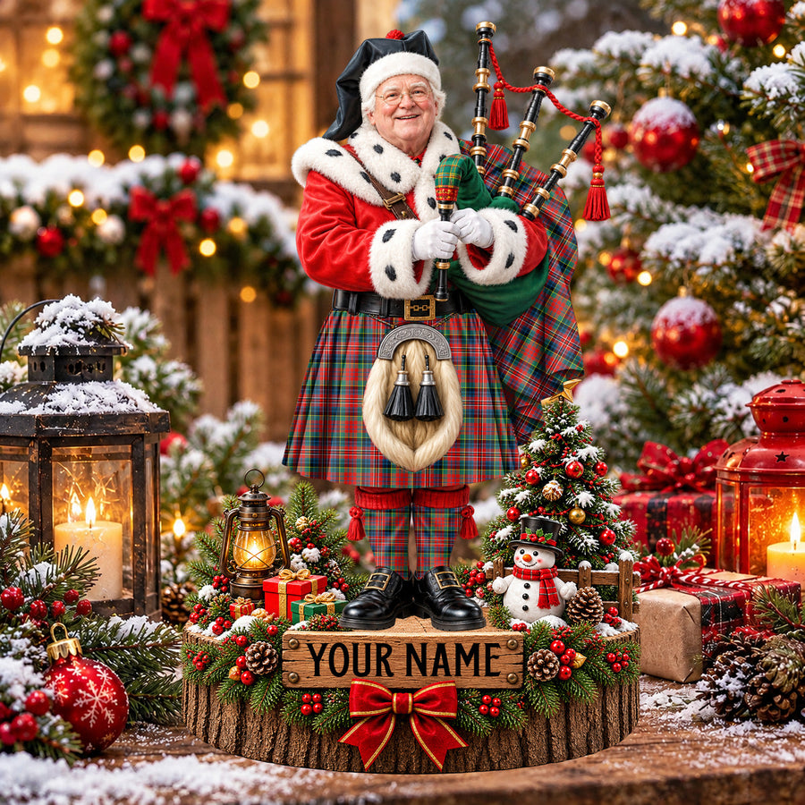 Personalized Christmas piper plaque in the MacPherson Ancient tartan, standing on a snowy log base with a name plaque