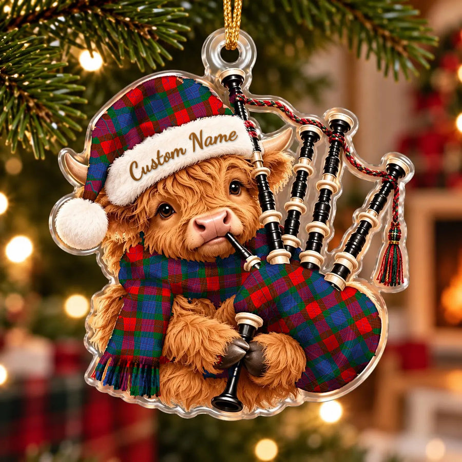Acrylic Highland cow calf ornament playing the bagpipes, in a MacQuarrie Modern copy tartan Santa hat, scarf and pipe bag, with a custom name on the hat
