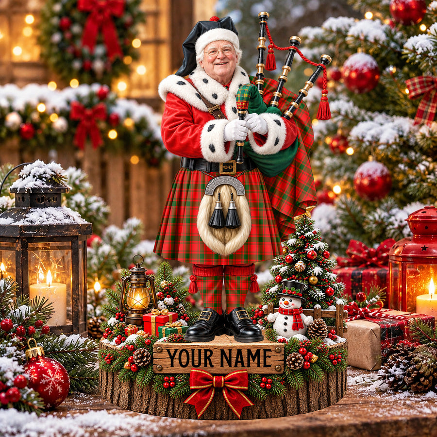 Personalized Christmas piper plaque in the MacQuarrie Modern tartan, standing on a snowy log base with a name plaque