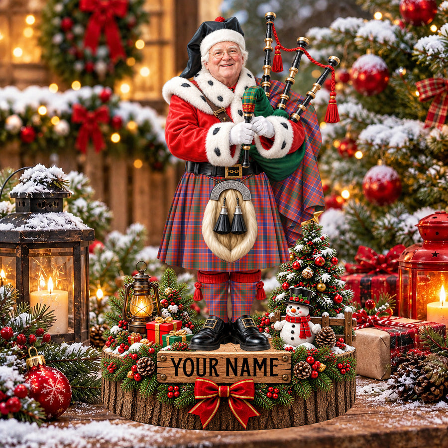 Personalized Christmas piper plaque in the MacRae Ancient tartan, standing on a snowy log base with a name plaque