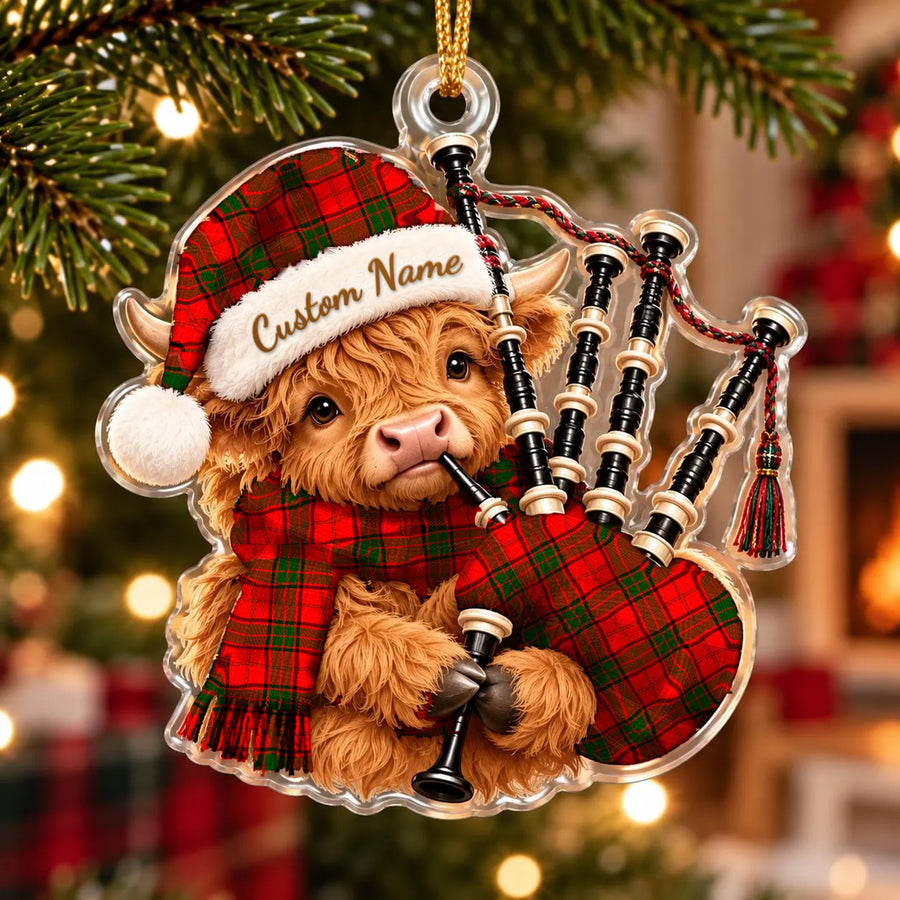 Acrylic Highland cow calf ornament playing the bagpipes, in a Maxwell Modern tartan Santa hat, scarf and pipe bag, with a custom name on the hat