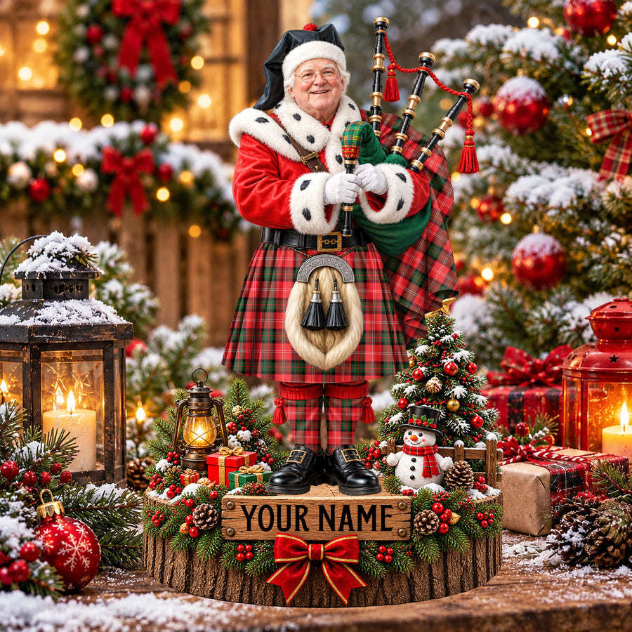 Personalized Christmas piper plaque in the Nesbitt Modern tartan, standing on a snowy log base with a name plaque