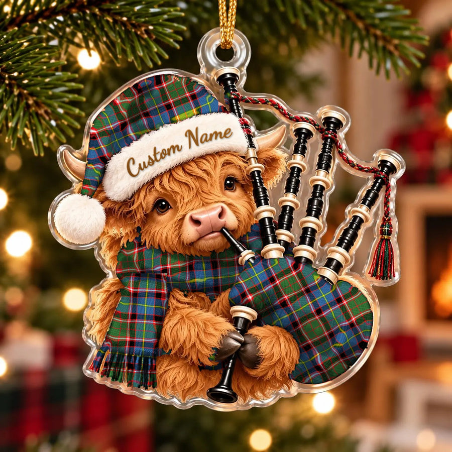 Acrylic Highland cow calf ornament playing the bagpipes, in a Norvel (Stirling) tartan Santa hat, scarf and pipe bag, with a custom name on the hat