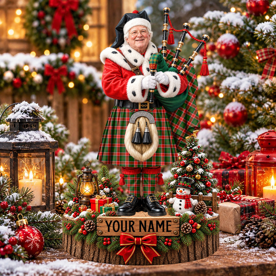 Personalized Christmas piper plaque in the Pollock Modern tartan, standing on a snowy log base with a name plaque