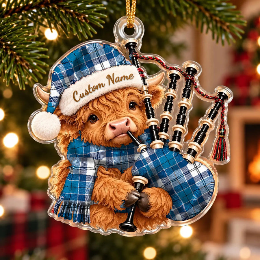 Acrylic Highland cow calf ornament playing the bagpipes, in a Roberton tartan Santa hat, scarf and pipe bag, with a custom name on the hat