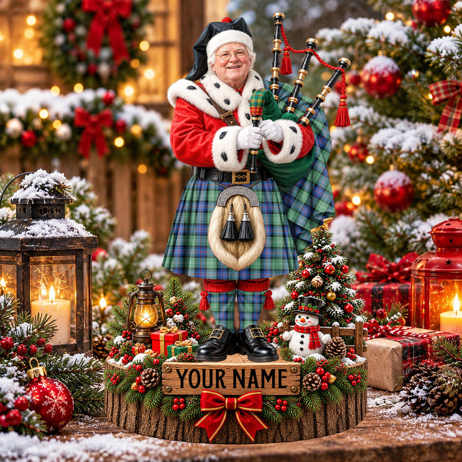 Personalized Christmas piper plaque in the Sutherland Old Ancient tartan, standing on a snowy log base with a name plaque