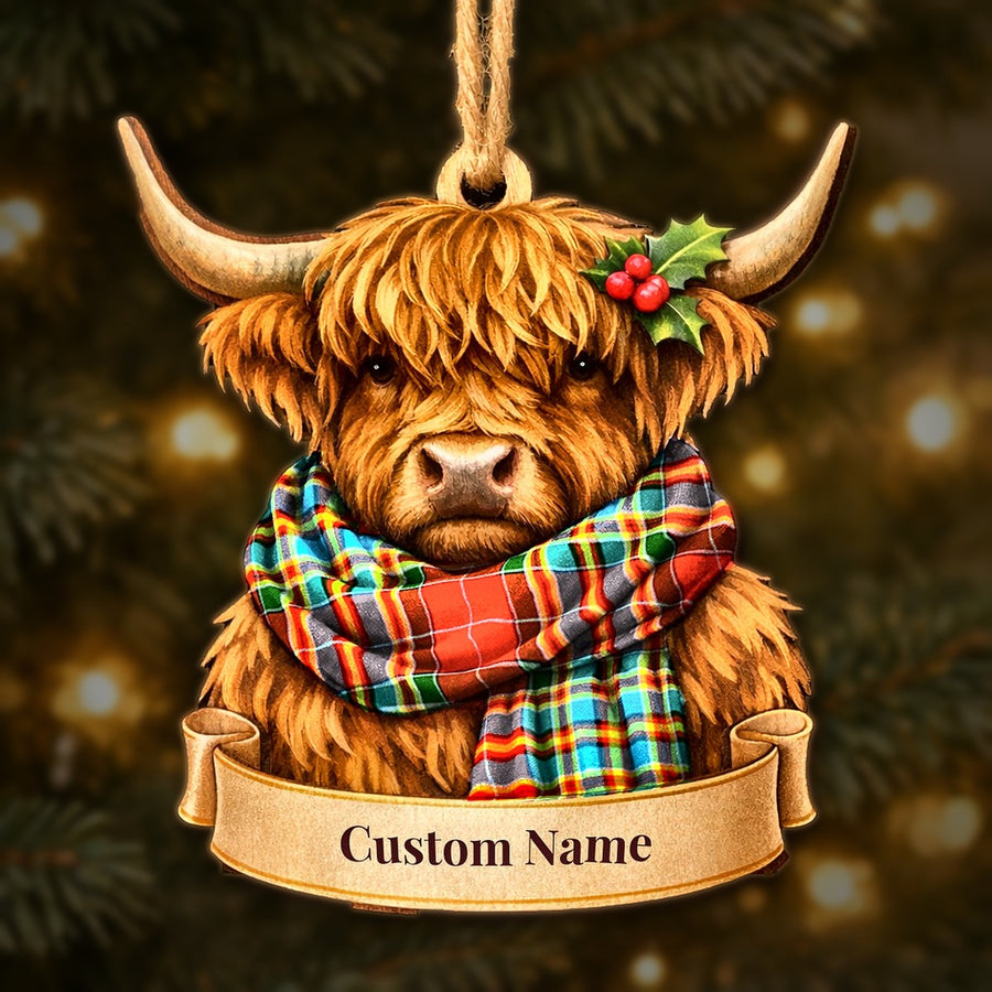 Wooden Highland cow Christmas ornament wearing a Chattan tartan scarf, with a ribbon banner for a custom name