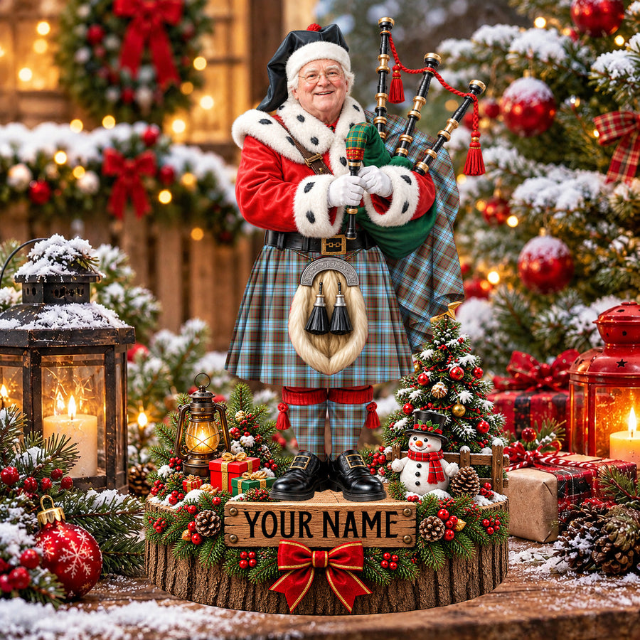 Personalized Christmas piper plaque in the Anderson Ancient tartan, standing on a snowy log base with a name plaque