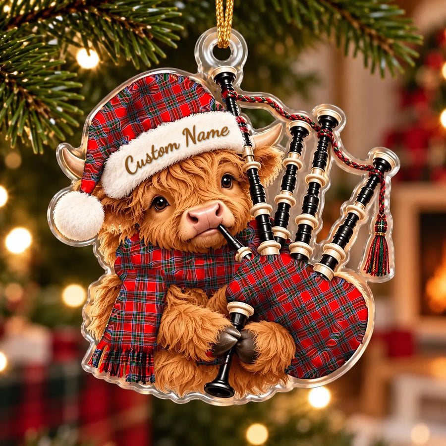 Acrylic Highland cow calf ornament playing the bagpipes, in a Binning tartan Santa hat, scarf and pipe bag, with a custom name on the hat