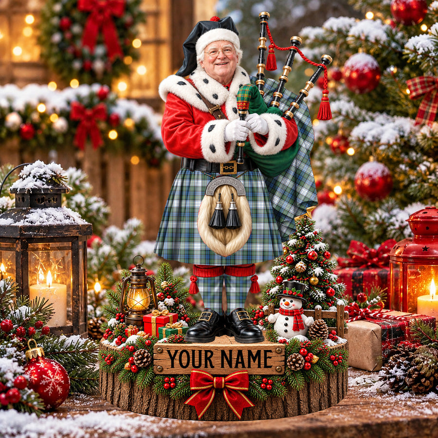 Personalized Christmas piper plaque in the Campbell Dress Ancient tartan, standing on a snowy log base with a name plaque