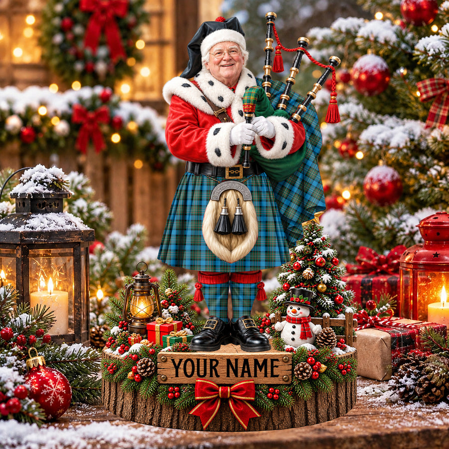 Personalized Christmas piper plaque in the Fergusson Ancient tartan, standing on a snowy log base with a name plaque