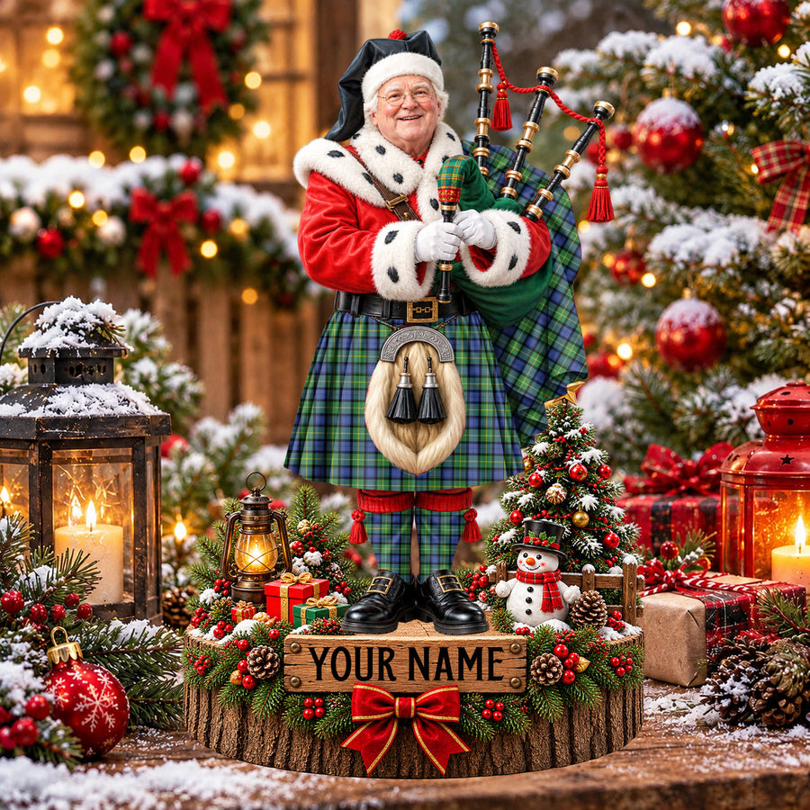 Personalized Christmas piper plaque in the Gordon Old Ancient tartan, standing on a snowy log base with a name plaque