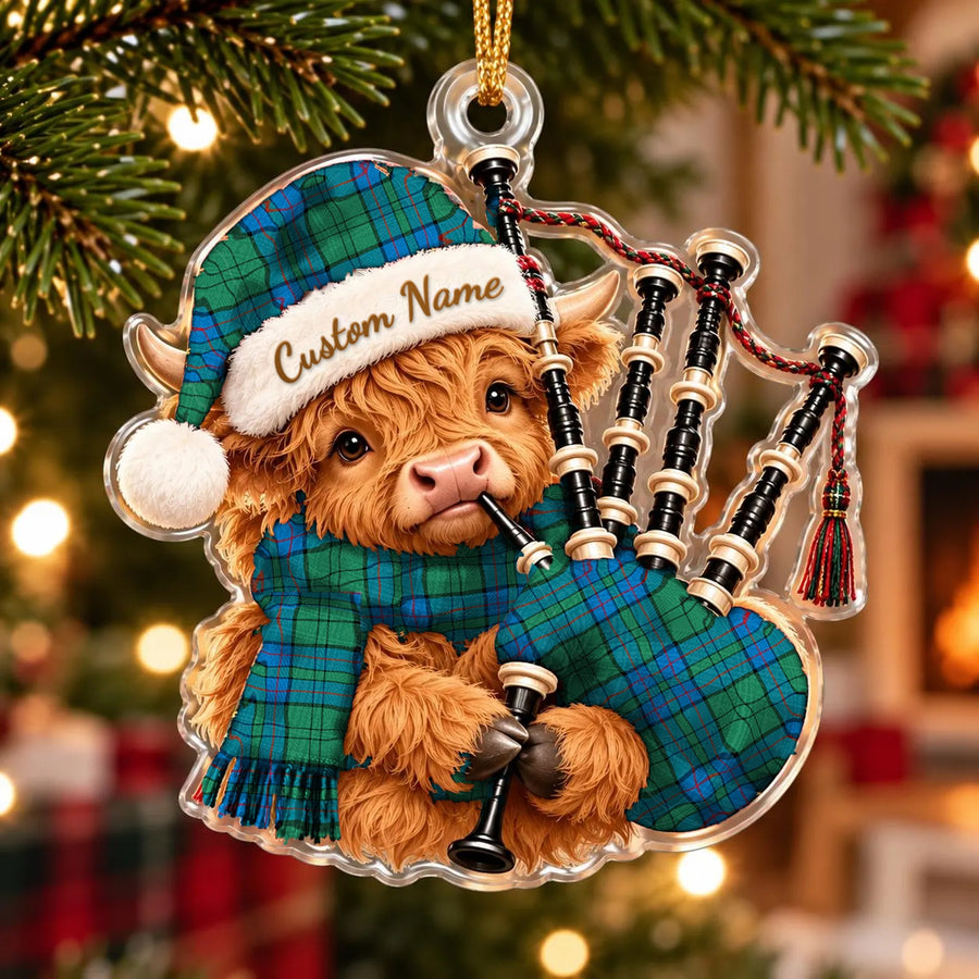 Acrylic Highland cow calf ornament playing the bagpipes, in a Lockhart tartan Santa hat, scarf and pipe bag, with a custom name on the hat