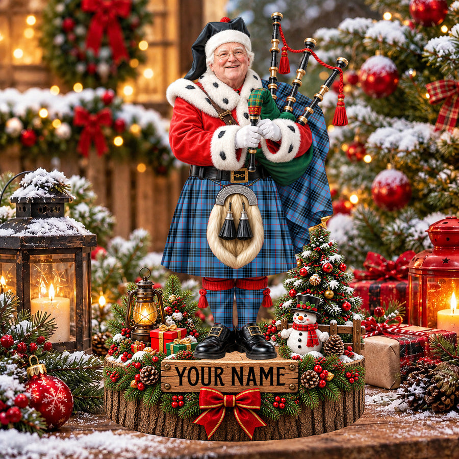 Personalized Christmas piper plaque in the MacKay Blue tartan, standing on a snowy log base with a name plaque