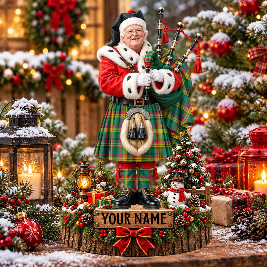 Personalized Christmas piper plaque in the MacMillan Old Ancient tartan, standing on a snowy log base with a name plaque