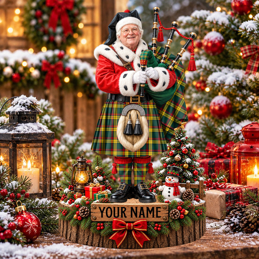 Personalized Christmas piper plaque in the MacMillan Old Modern tartan, standing on a snowy log base with a name plaque