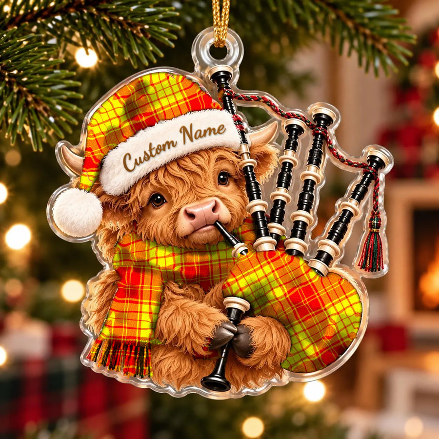 Acrylic Highland cow calf ornament playing the bagpipes, in a MacMillan tartan Santa hat, scarf and pipe bag, with a custom name on the hat