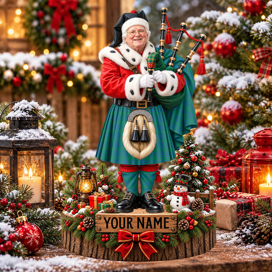 Personalized Christmas piper plaque in the Montgomery Ancient tartan, standing on a snowy log base with a name plaque