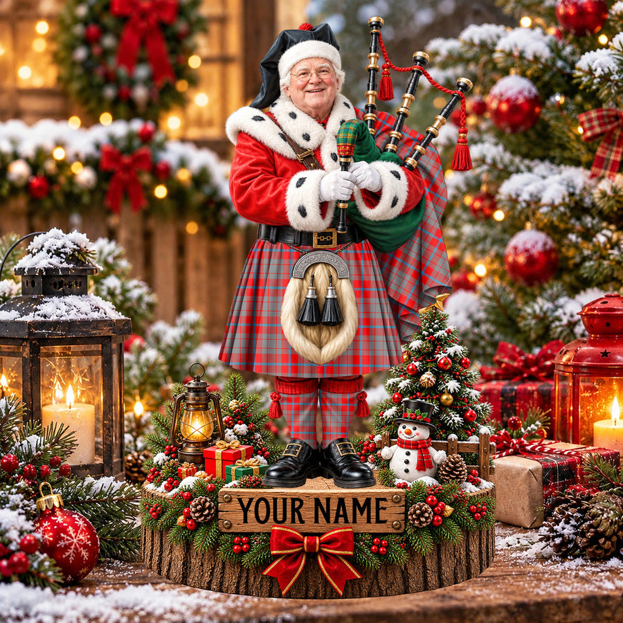 Personalized Christmas piper plaque in the Moubray tartan, standing on a snowy log base with a name plaque
