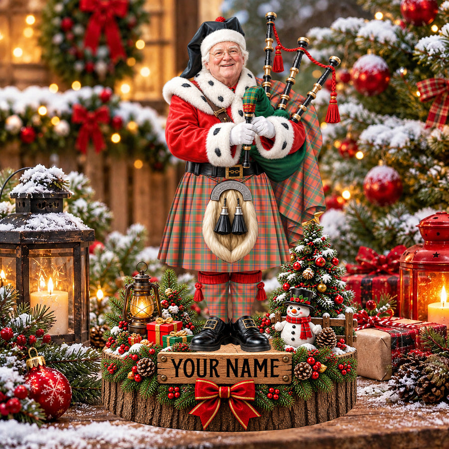 Personalized Christmas piper plaque in the Munro Ancient tartan, standing on a snowy log base with a name plaque