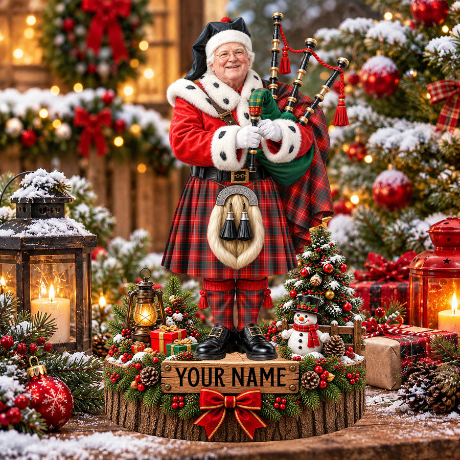 Personalized Christmas piper plaque in the Munro Modern 1 tartan, standing on a snowy log base with a name plaque
