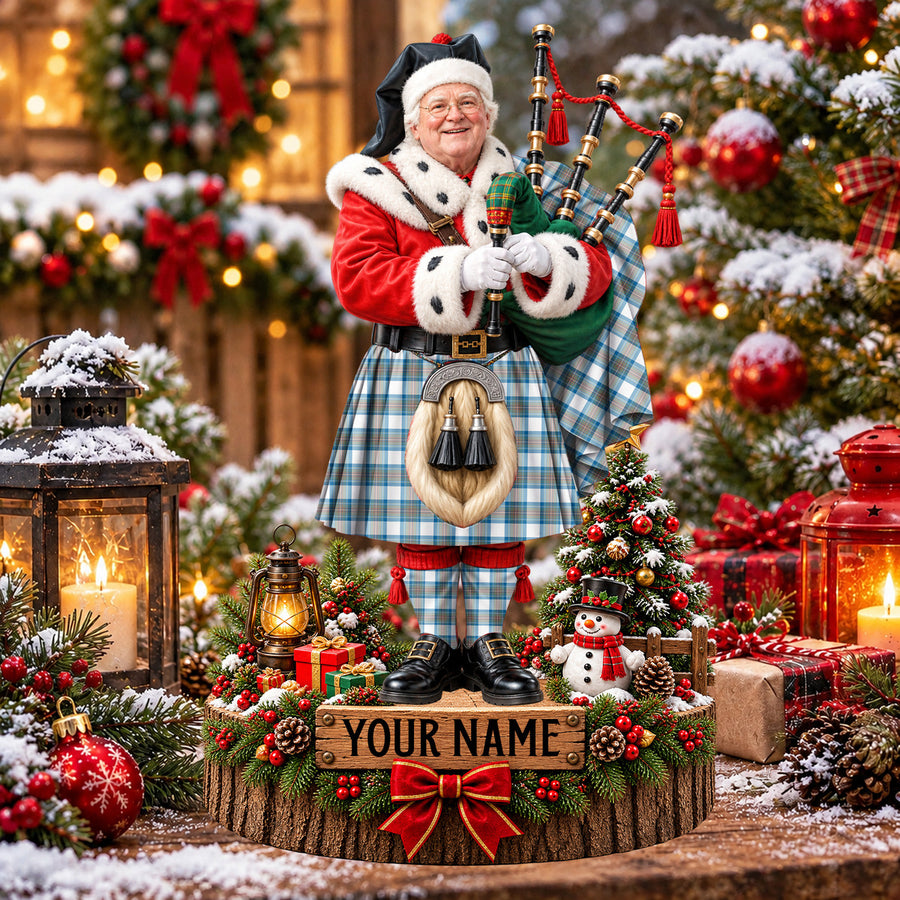Personalized Christmas piper plaque in the Stewart Muted Blue tartan, standing on a snowy log base with a name plaque
