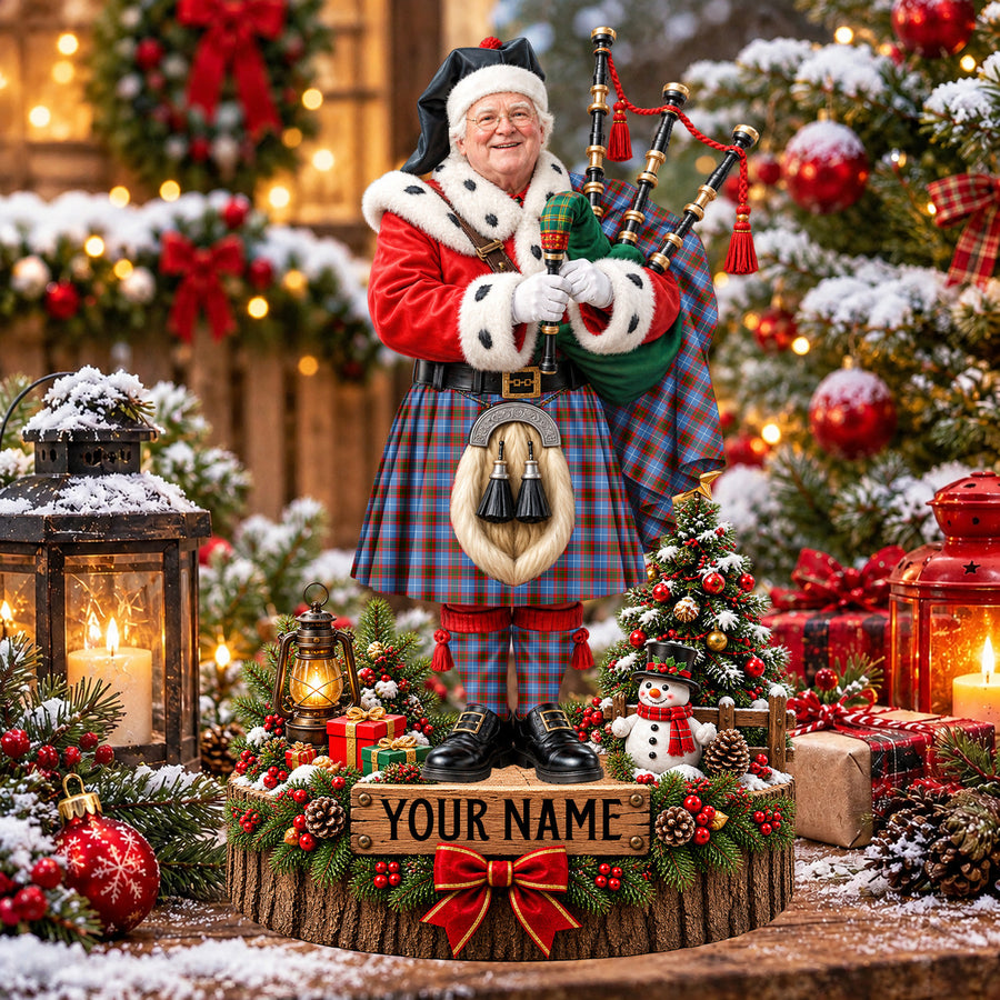Personalized Christmas piper plaque in the Trotter tartan, standing on a snowy log base with a name plaque