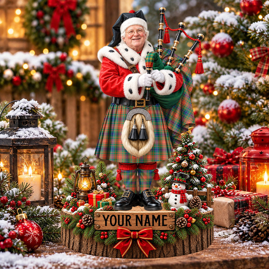 Personalized Christmas piper plaque in the Wilson Ancient tartan, standing on a snowy log base with a name plaque