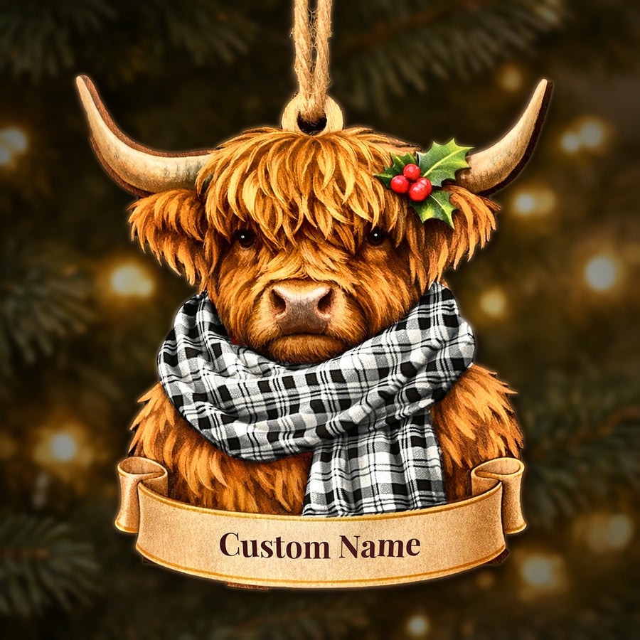Wooden Highland cow Christmas ornament wearing a Scott Black & White Ancient tartan scarf, with a ribbon banner for a custom name